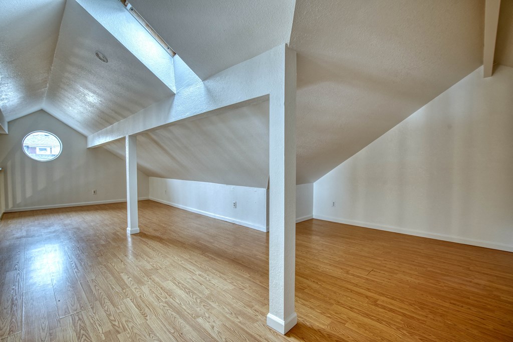 an attic with a loft bed and hardwood floors