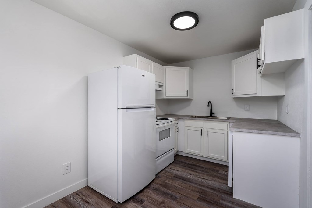 A white kitchen with a refrigerator, oven, and cabinets.