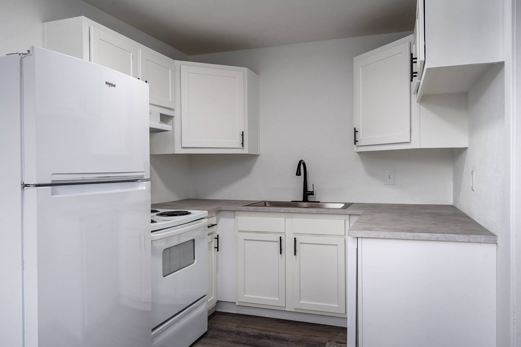 A white kitchen with a refrigerator, oven, and cabinets.