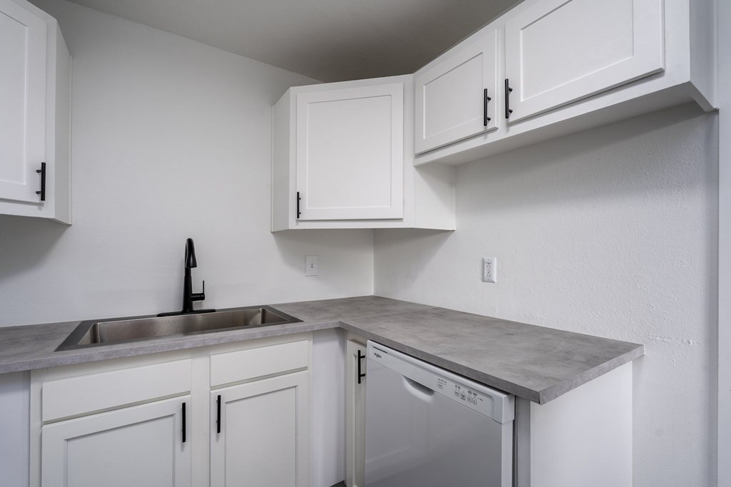 A kitchen with white cabinets and a grey countertop.