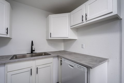 A kitchen with white cabinets and a grey countertop.