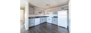 A kitchen with white appliances and wooden floors.