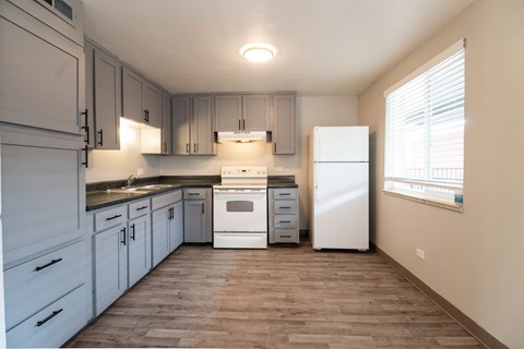 A kitchen with white appliances and wooden floors.