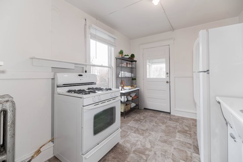 A white kitchen with a stove and a refrigerator.