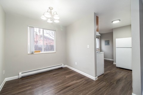 A room with a window and a white refrigerator.