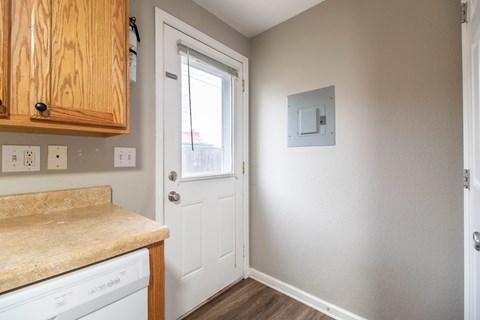 A small room with a door and a light switch on the wall.