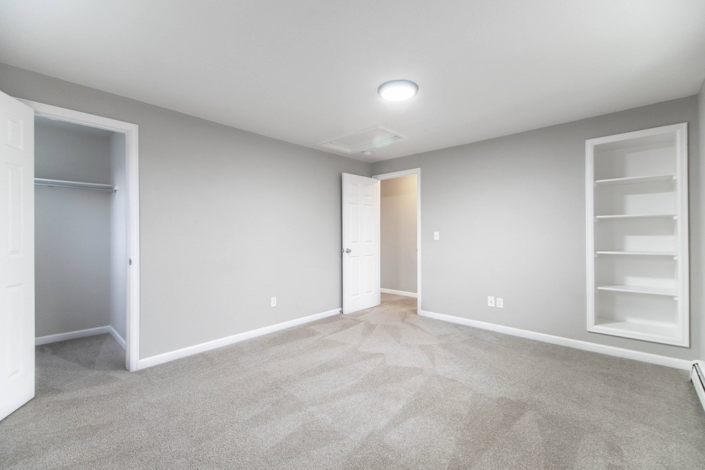 A spacious room with a carpeted floor and white walls.