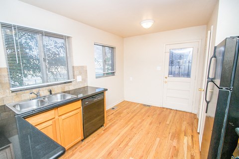 A kitchen with wooden cabinets and a black fridge.