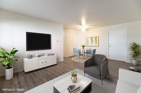 A living room with a grey couch, a white coffee table, and a television on the wall.