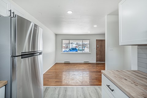 A kitchen with a refrigerator, wooden countertops, and a view of a snowy landscape through a window.