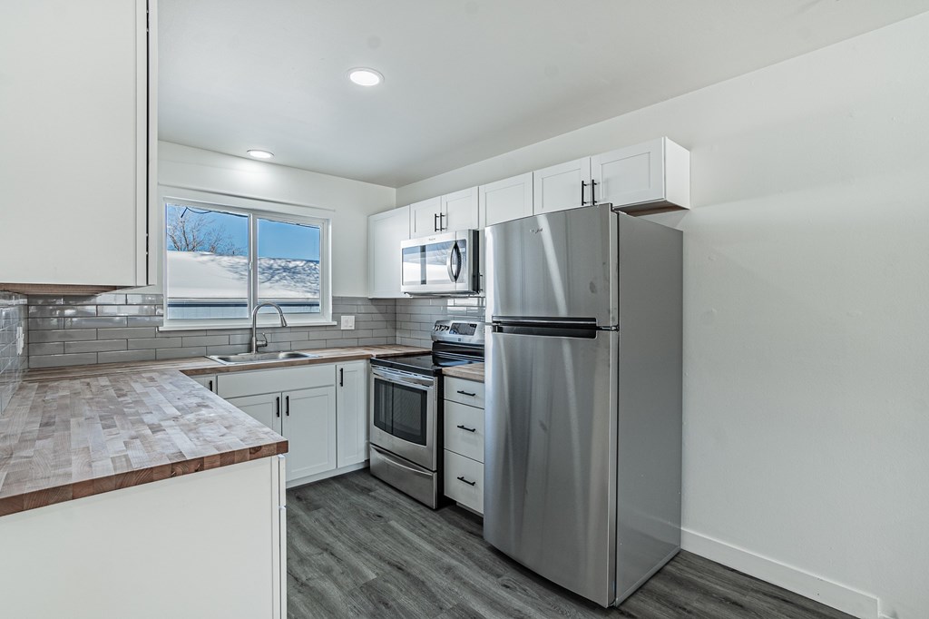 A modern kitchen with stainless steel appliances and a wooden countertop.
