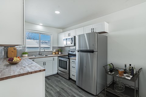 A modern kitchen with stainless steel appliances and a wooden countertop.