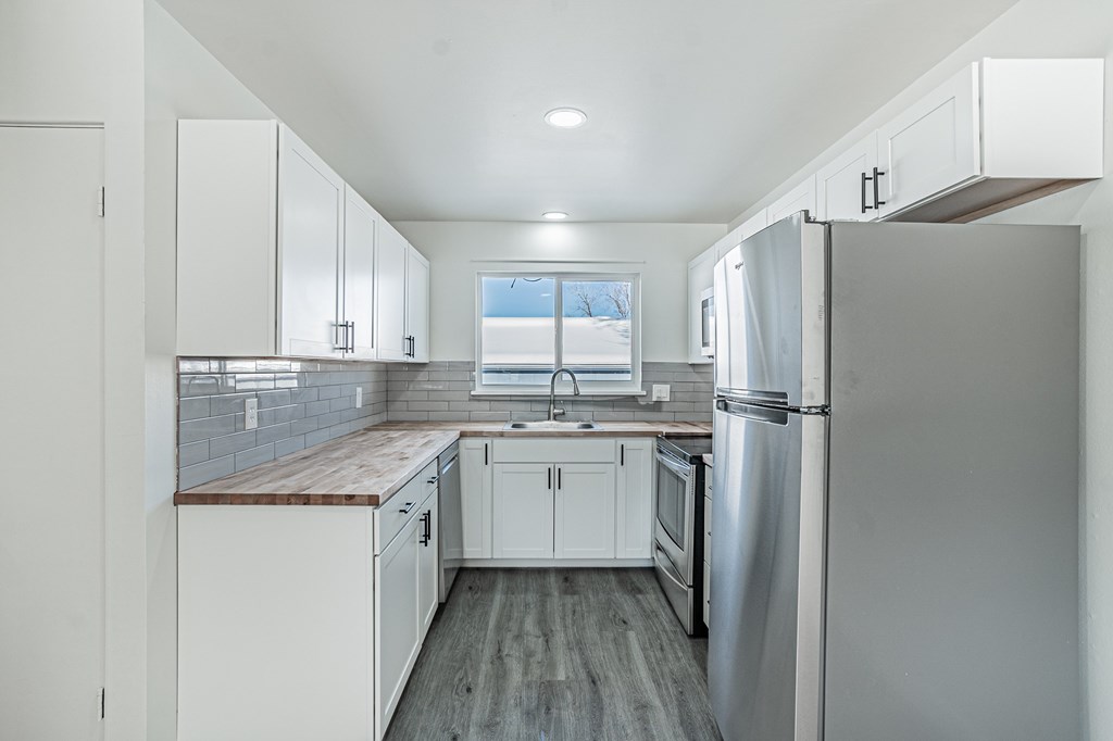 A kitchen with white cabinets and a stainless steel refrigerator.