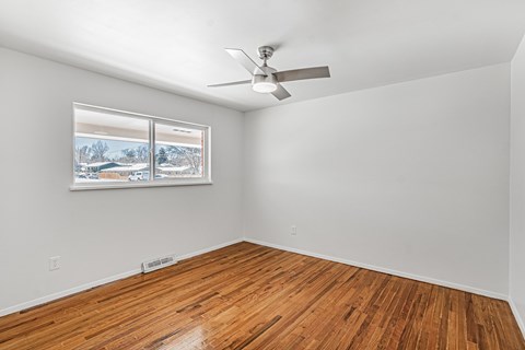 A room with a ceiling fan and a window showing a snowy landscape outside.