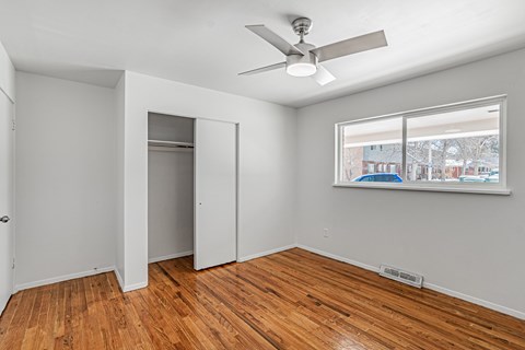 A room with a ceiling fan and a window showing a view of a snowy landscape outside.