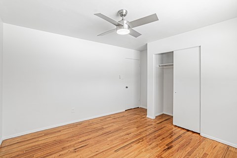 A room with a ceiling fan and wooden flooring.