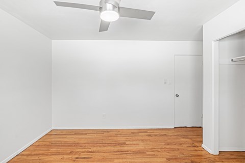 A room with a ceiling fan and wooden flooring.