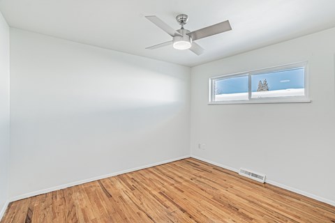A room with a ceiling fan and a window showing a snowy landscape outside.