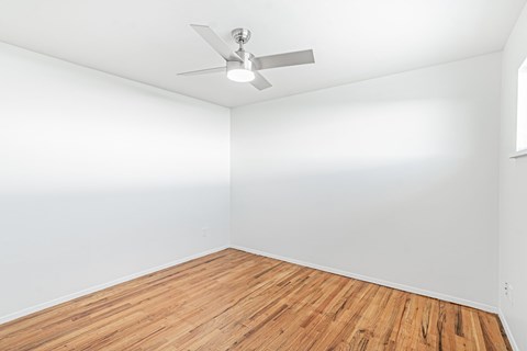A room with a ceiling fan and wooden flooring.