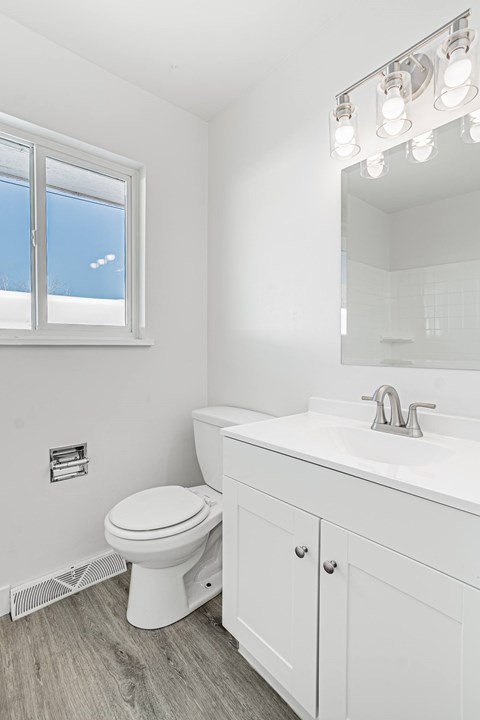A white bathroom with a toilet, sink, and mirror.