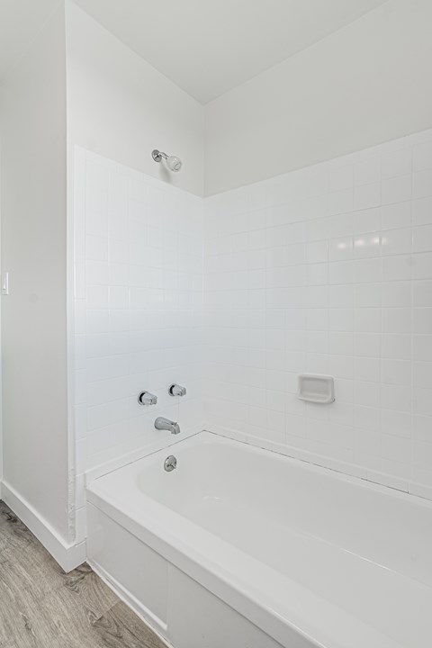 A white bathtub with a shower head and faucet.