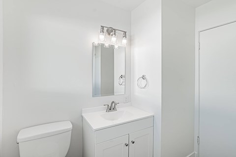 A white bathroom with a toilet, sink, and mirror.