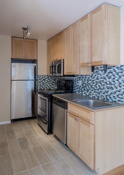A kitchen with wooden cabinets and a black and white tiled backsplash.