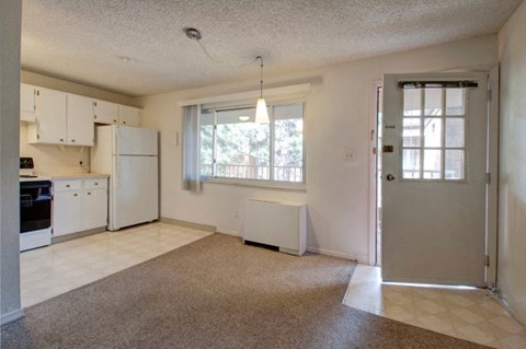 A kitchen with white cabinets and a window with blinds.