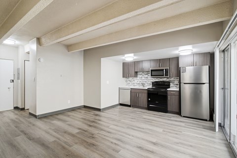 A kitchen with a refrigerator, microwave, and oven.