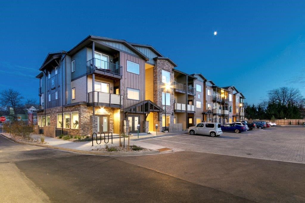 a row of apartment buildings at night with a parking lot