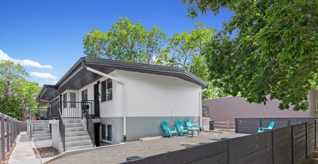 a small white house with blue chairs in front of it