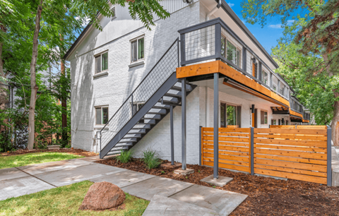 A modern house with a grey exterior and a wooden fence.
