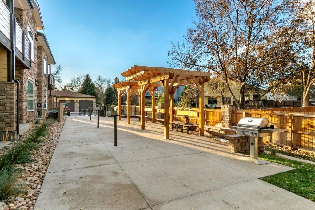 a covered patio with a grill and a wooden structure