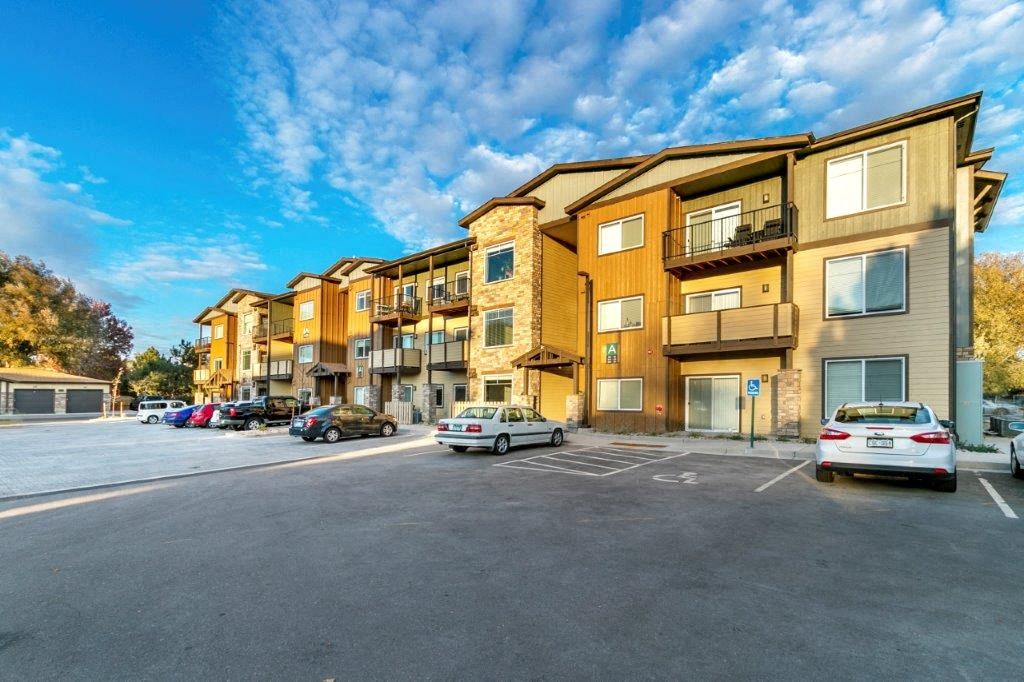 an empty parking lot with cars in front of apartment buildings
