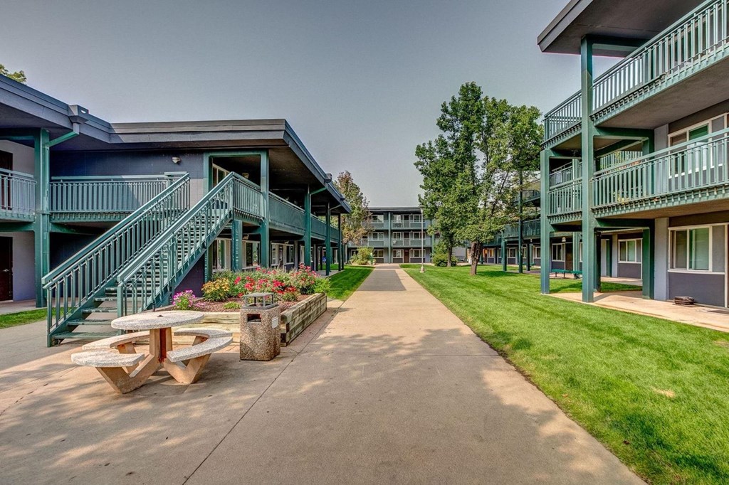 a sidewalk between two buildings with a picnic table