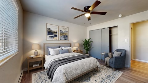 A bedroom with a large bed, a ceiling fan, and a chair.