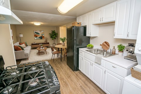 A kitchen with a black refrigerator and white cabinets.