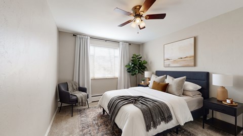 A bedroom with a bed, chair, and a ceiling fan.