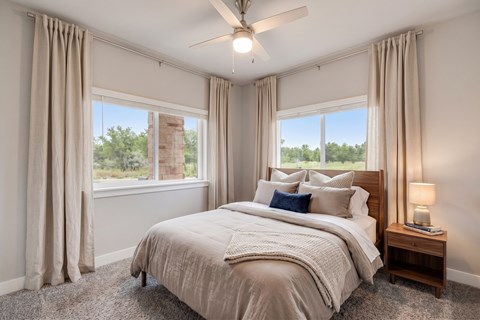 A bedroom with a large bed and a ceiling fan.