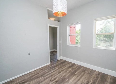 A room with a wooden floor and a window showing a red building outside.