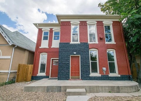 A red and blue two story house with a red door.