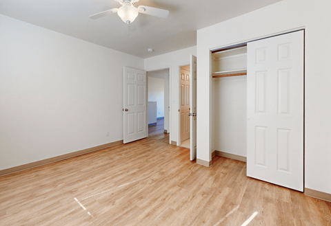 a living room with white walls and wood flooring and a closet