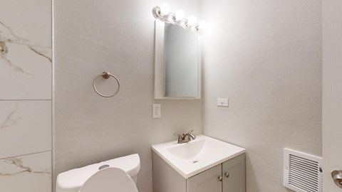 A bathroom with a white toilet, sink, and mirror.
