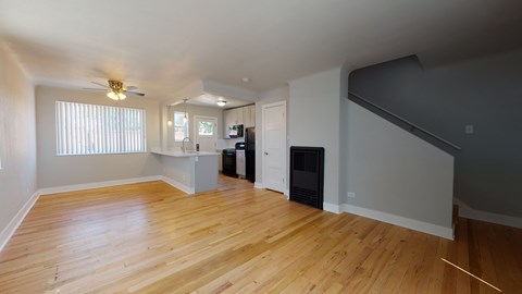 A spacious room with wooden floors and a ceiling fan.