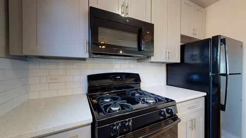 A black stove top oven sits under a microwave in a kitchen.