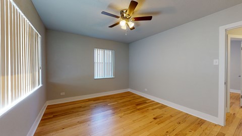 A room with a ceiling fan and wooden flooring.