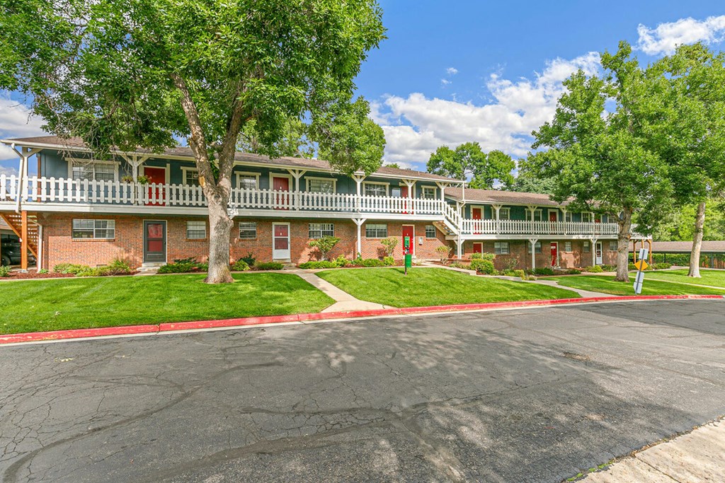 A large tree is in front of a two-story apartment building.