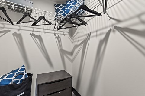 A room with a bed, a dresser and a wall with hangers hanging on it.