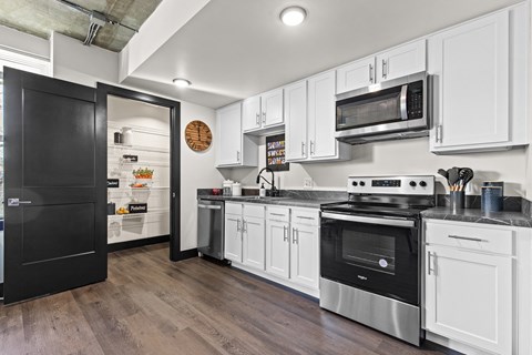 A kitchen with black and white cabinets and a black refrigerator.