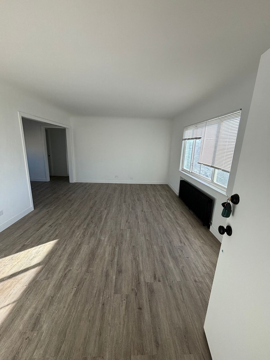 an empty living room with wood floors and a window